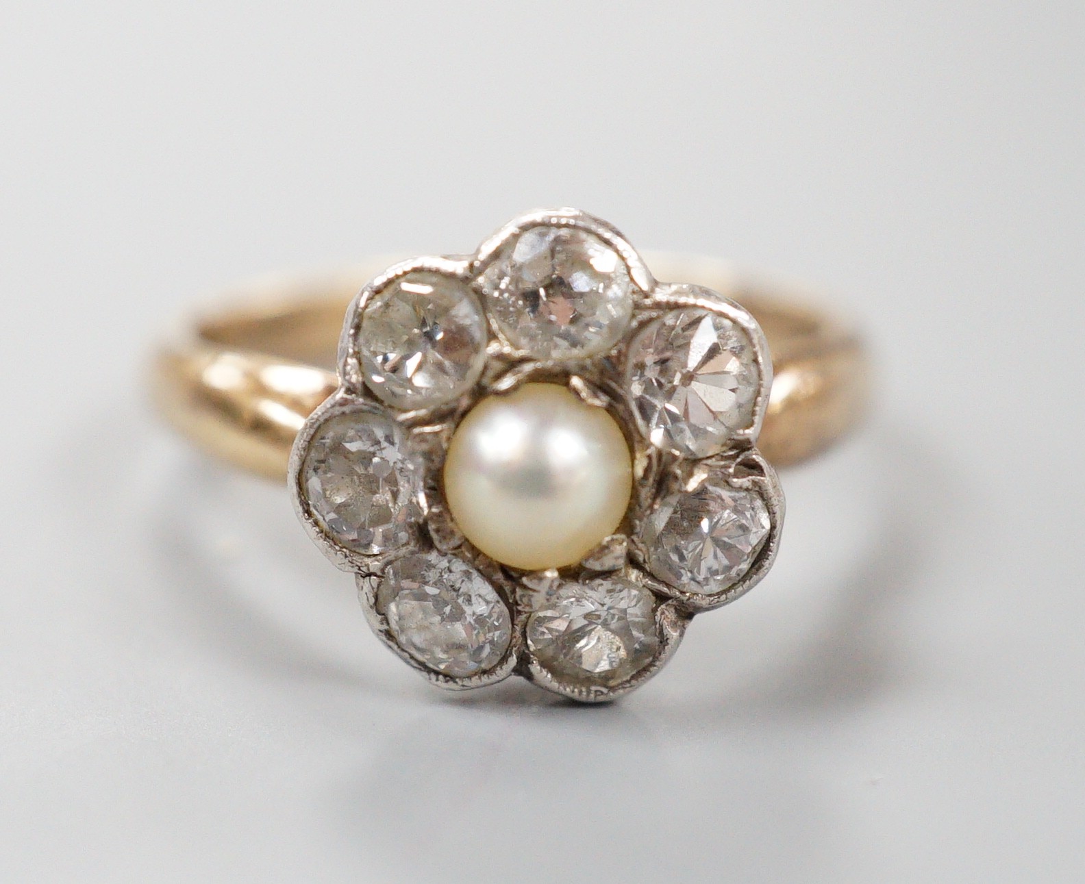 A late Victorian yellow metal, single stone split pearl and seven stone diamond set circular cluster ring, size I, gross weight 3 grams.